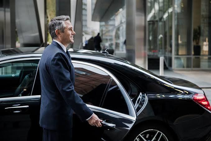 Professional executive chauffeur opening door for client in London